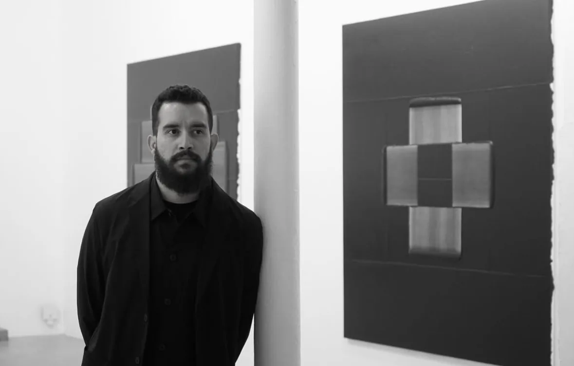 Kmilo Morales en una sala junto a dos de sus obras