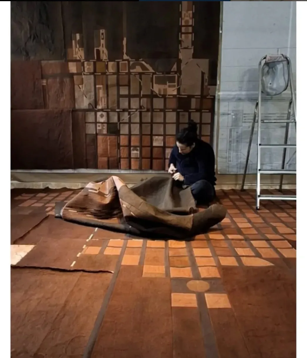 Yanelis Mora trabajando en el suelo con una gran pieza textil